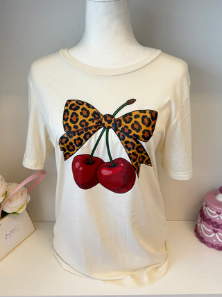 Neutral beige t-shirt with colorful hand-drawn bows in red, blue, orange, and green – cute and trendy boutique tee.