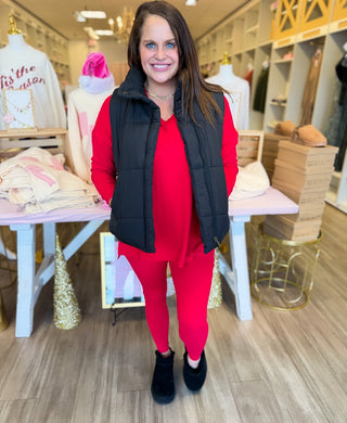 Woman in red outfit with black vest standing in a store