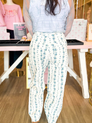 Blue Willow Drawstring Pants with cream base and blue floral print, wide-leg fit, and adjustable drawstring waist – styled with a sheer lace sleeve top.