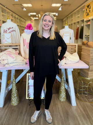 Woman standing in a store with clothing and mannequins in the background