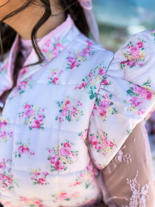 Soft quilted vest with ruffle detail and florals and bow design. Pockets. 