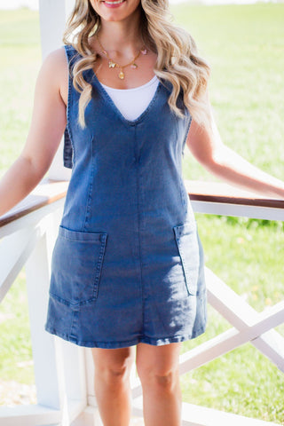 A blue overall dress with adjustable straps and an above the knee length. 