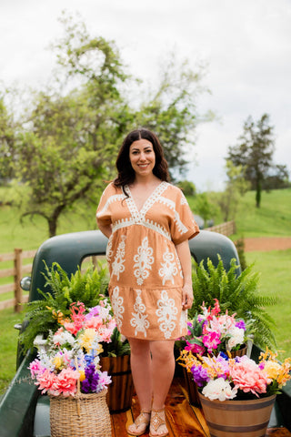 A beautiful tan baby doll dress with a lace like pattern throughout. This knee length dress with v neck is a summer must. 