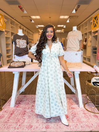 This floral maxi dress is the ultimate boutique must-have for fall. Designed with romantic puff sleeves, a flattering tie-front detail, and a flowy silhouette, it’s perfect for everything from a brunch outfit to a weekend stroll. The soft white floral print makes it easy to style, whether you’re dressing it up with boots or keeping it casual. 