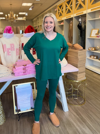 Woman in a green outfit standing in a store with clothing and decor in the background