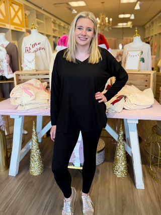 Woman in a black outfit standing in a store with mannequins and clothing in the background