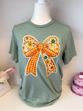 Sage green graphic t-shirt with large vintage floral bow and orange gingham detail – retro fall style boutique tee.