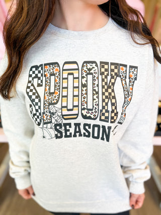 Spooky Season sweatshirt with checkered, leopard, striped, and festive Halloween prints—cozy gray fall pullover for pumpkin patch, trick-or-treat, and autumn style.