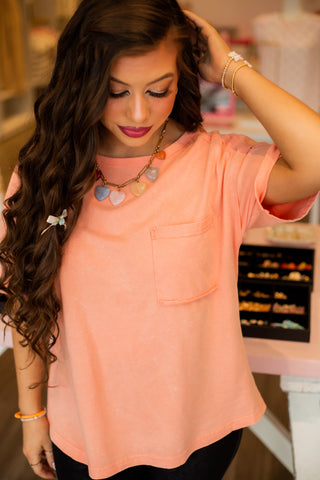 Mineral wash tee available on pink, light orange, and grey. Comes in small through large. 