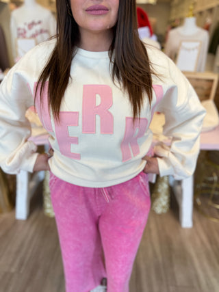 Person wearing a white sweatshirt with pink text and pink pants in an indoor setting